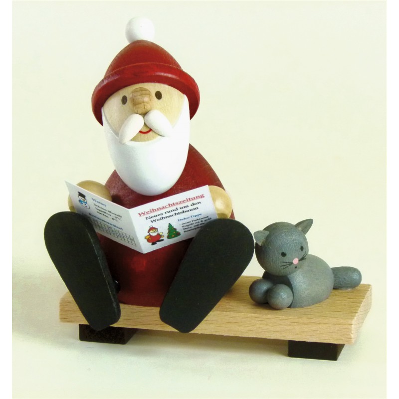 Weihnachtsmann mit Zeitung und Katze auf Bank